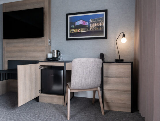 A hotel room featuring a desk, chair, and television, designed for comfort and convenience.