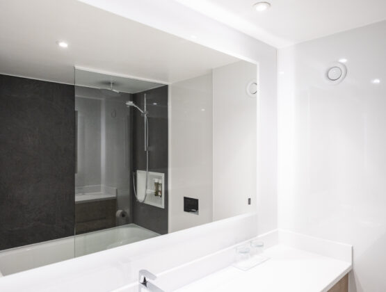 A contemporary bathroom, showcasing a clear glass shower and a modern sink setup featuring a large mirror.