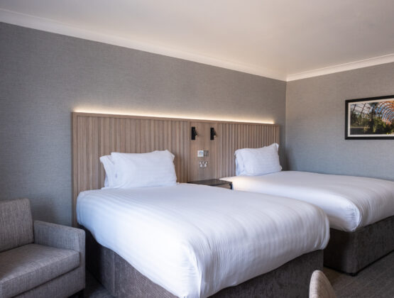 Two beds in a hotel room with a desk and chair, providing a comfortable and functional space for guests