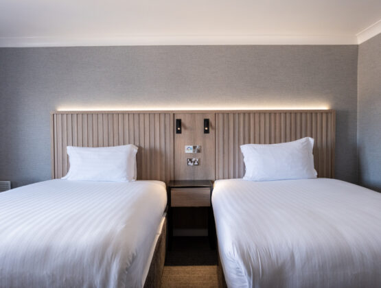 A hotel room featuring two beds, both dressed in crisp white sheets, offering a comfortable sleeping arrangement.